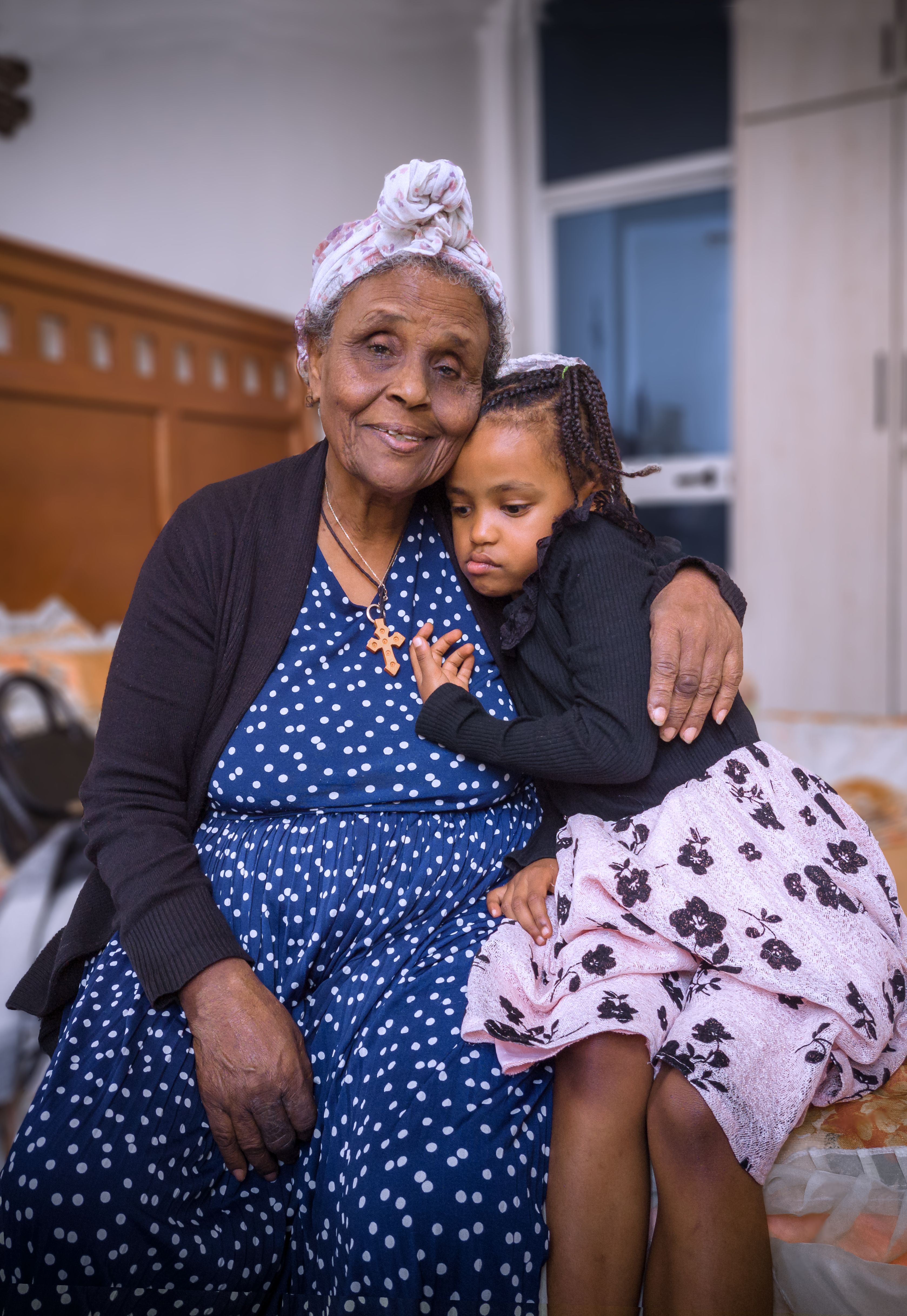 An elderly woman embracing her granddaughter at home